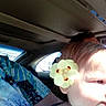 Esme is registered to the contest to win money with this photo: adult, blue, car, casual, child, closeup, daylight, face, flower, hair, interior, patterned_clothing, person, portrait, seat, seatbelt, side_view, sunlight, window, yellow