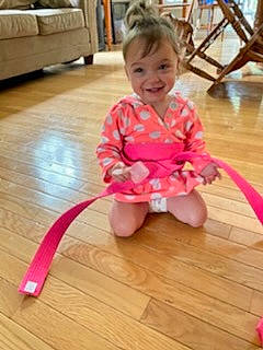 Delilah is registered to the contest to win money with this photo: baby_toddler_clothing, child, floor, flooring, fun, hair, happy, hardwood, human_leg, joy, laminate_flooring, leisure, magenta, person, pink, skin, smile, thumb, toddler, varnish