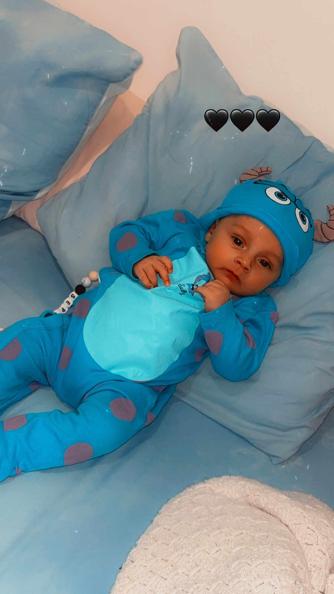 Joseph a rejoint le concours — aidez-le/la à gagner de superbes lots ! baby, infant, blue_onesie, hat, monster_costume, couch, pillows, blanket, indoor, child, cute, adorable, relaxed, lying_down, looking_at_camera, black_hearts, soft_lighting, cozy, home, portrait