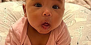 Isla joined the competition — help win amazing prizes! baby, infant, child, cute, pigtails, pink_clothing, bed, pillow, expression, surprised, skin, hand, foot, indoors, home, soft, cushion, person, portrait, sitting