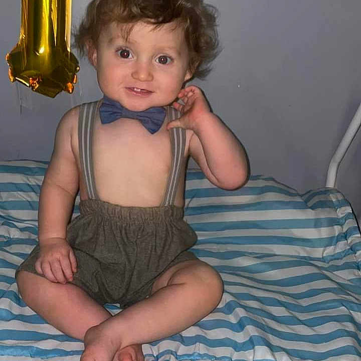 Emmitt joined the competition — help win amazing prizes! baby, balloon, bed, bedroom, bodypart, clothing, costume, face, finger, furniture, hat, head, indoors, mortarshell, partyhat, person, photography, portrait, room, weapon