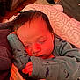 baby, sleeping, newborn, infant, clothing, blanket, hand, face, peaceful, cozy, indoors, portrait, cute, resting, soft_light, warm_tone, dinosaur_print, young_child, human, sleep