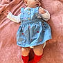 baby, infant, child, blue_dress, red_socks, blanket, soft_texture, lying_down, curious_expression, indoor, cozy, embroidered_clothing, cute, small_ears, short_hair, person, footwear, colorful_clothing, relaxed, casual