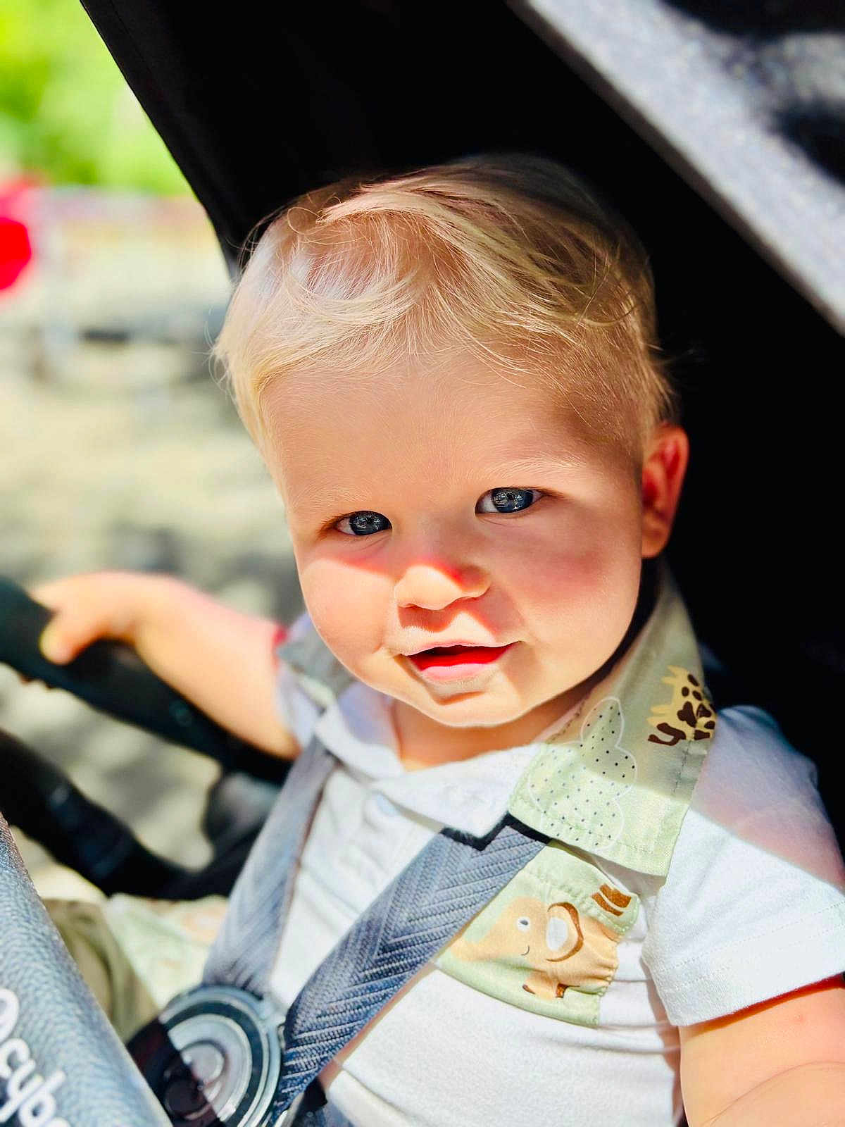 Camille a rejoint le concours — aidez-le/la à gagner de superbes lots ! child, toddler, baby, blond_hair, blue_eyes, stroller, safety_strap, sunlight, outdoor, cute, portrait, baby_clothes, smile, closeup, daylight, seatbelt, infant, happy, person, baby_face