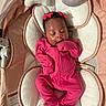 baby, infant, sleeping, pink_onesie, bows, baby_bouncer, plush_toys, moon, cloud, soft_cushion, indoors, peaceful, cute, newborn, child, cozy, resting, fabric, comfort, adorable