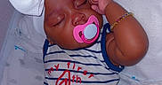 Serenity is registered to the contest to win money with this photo: baby, infant, sleeping, pacifier, headband, bow, bracelet, striped_clothing, red_shorts, white_blanket, cute, child, indoors, resting, adorable, young_child, peaceful, lying_down, soft_texture, portrait