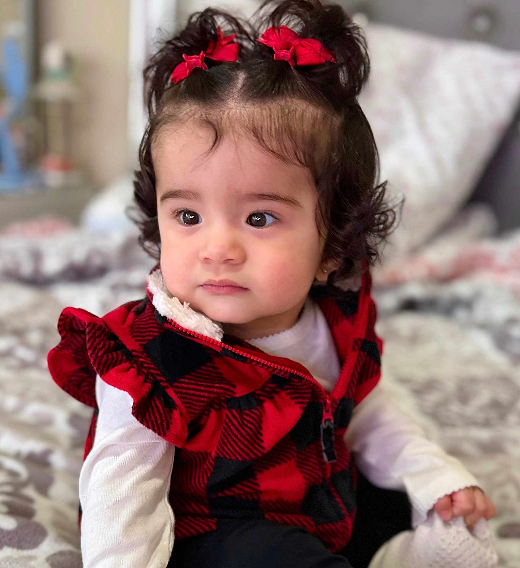 Abigail joined the competition — help win amazing prizes! bed, black_checkered, blanket, child, clothing, cozy, curly_hair, cute, expression, face, indoor, person, portrait, red_bows, red_vest, sitting, soft_lighting, toddler, white_shirt, young_child