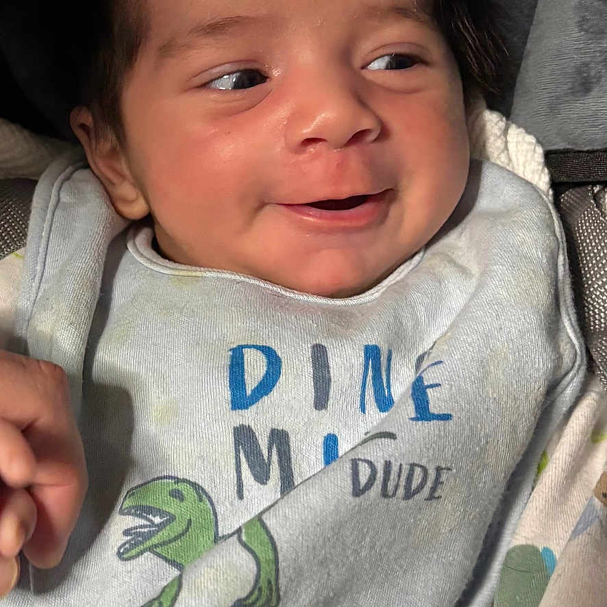 Draven joined the competition — help win amazing prizes! baby, baby_clothes, bib, child, closeup, clothing, cozy, cute, dinosaur, expression, face, happy, indoors, infant, newborn, person, portrait, smile, soft_lighting, wearing