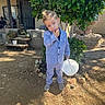 child, boy, suit, outdoor, yard, bucket, shoes, plant, tree, porch, house, dirt, sunlight, shadow, casual, thoughtful, posing, greenery, fashion, daytime