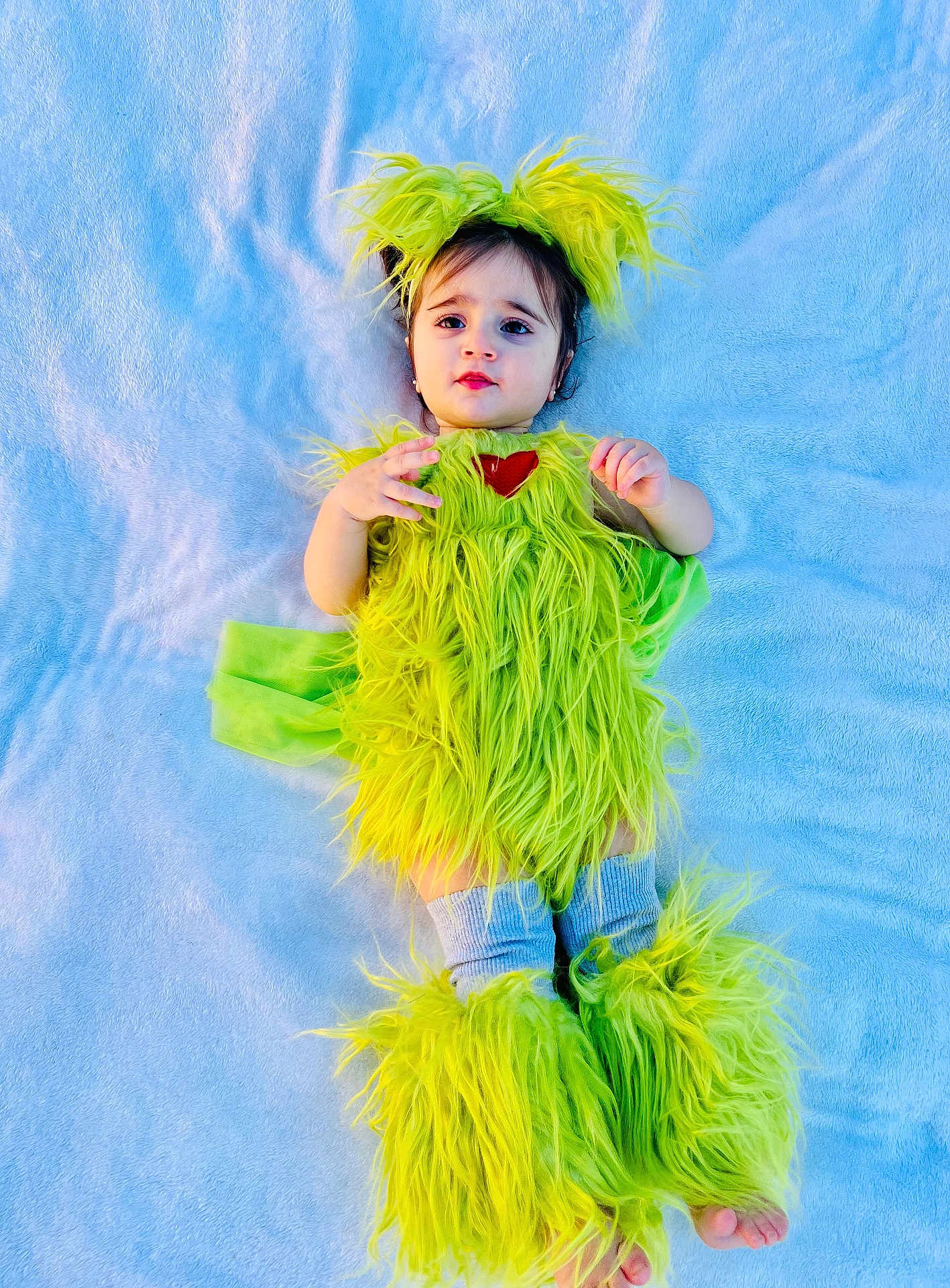 Teresa is registered to the contest to win money with this photo: baby, child, costume, green, fuzzy, leg_warmers, headpiece, blanket, blue, cute, infant, lying_down, soft_texture, portrait, smiling, eyes, hands, feet, young, cozy