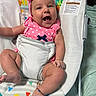 baby, infant, child, smiling, open_mouth, pink_bow, headband, polka_dots, pink_clothing, baby_seat, reclining, indoor, portrait, face, eyes, arms, legs, colorful, patterned_background, safe_sleeping_area