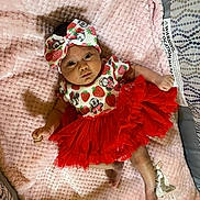Milani is registered to the contest to win money with this photo: baby, infant, tutu, headband, blanket, pink, red, cute, clothing, lying_down, bed, patterned, soft, person, child, face, foot, hand, decor, cozy