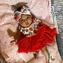 baby, infant, tutu, headband, blanket, pink, red, cute, clothing, lying_down, bed, patterned, soft, person, child, face, foot, hand, decor, cozy