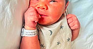 Zayden is registered to the contest to win money with this photo: baby, bed, blanket, cute, expression, face, hand, hospital_bracelet, indoors, infant, moon, newborn, onesie, person, portrait, resting, skin, sleepwear, stars, young_child