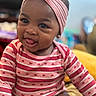 baby, infant, smiling, headband, bow, striped_clothing, hearts, tongue_out, cute, portrait, indoors, happy, child, young, person, face, skin, sitting, apparel, fashion