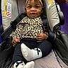 baby, infant, car_seat, headband, bow, leopard_print, clothing, black_leggings, white_socks, smile, happy, child, cute, indoor, person, seatbelt, fabric, portrait, young_child, comfort
