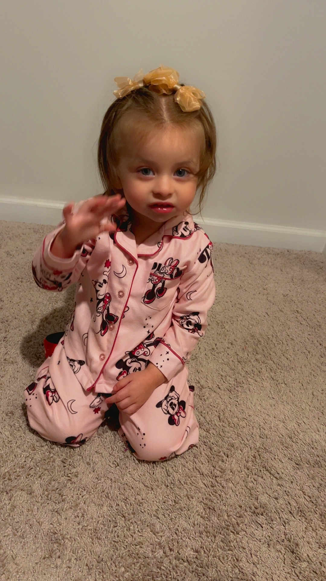 Valentina is registered to the contest to win money with this photo: child, toddler, pajamas, pink, carpet, indoor, kneeling, waving, girl, hair_bows, cute, smile, face, person, clothing, sleepwear, mickey_mouse, home, young_child, portrait