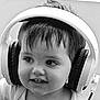 child, headphones, black_and_white, portrait, close_up, cute, young_child, smile, hair, face, expression, indoors, person, technology, listening, baby, earphones, childhood, monochrome, happy