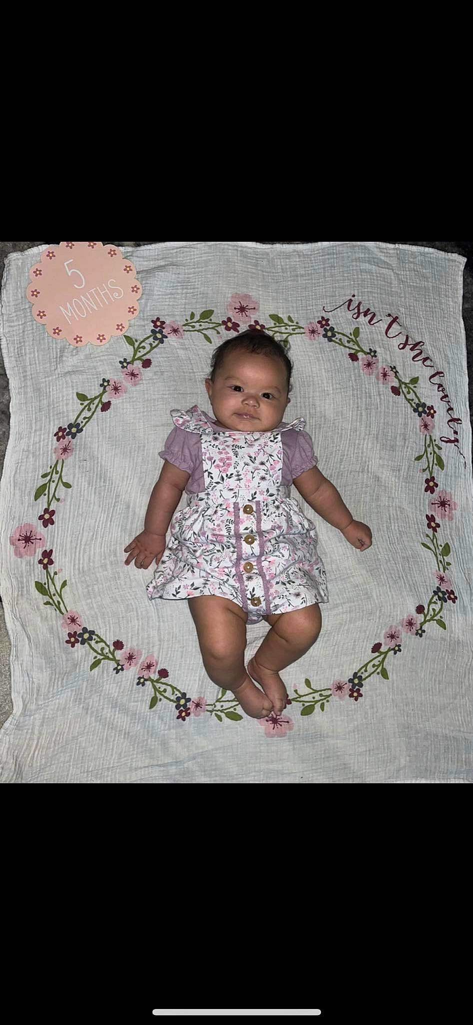 Gabriella is registered to the contest to win money with this photo: baby, baby_products, baby_toddler_clothing, child, day_dress, dress, embellishment, face, happy, linens, magenta, pattern, person, petal, pink, purple, rectangle, sleeve, smile, toddler