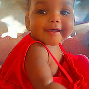 Alora is registered to the contest to win money with this photo: baby, child, smile, red_dress, portrait, face, cute, infant, happiness, indoors, skin, young_child, sitting, eyes, cheeks, person, clothing, closeup, expression, warmth