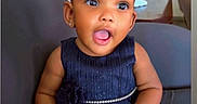 Alora is registered to the contest to win money with this photo: baby, child, girl, dress, navy_blue, pearl_belt, smiling, happy, sitting, chair, indoors, cute, skin, hair, earrings, portrait, expression, furniture, home, person