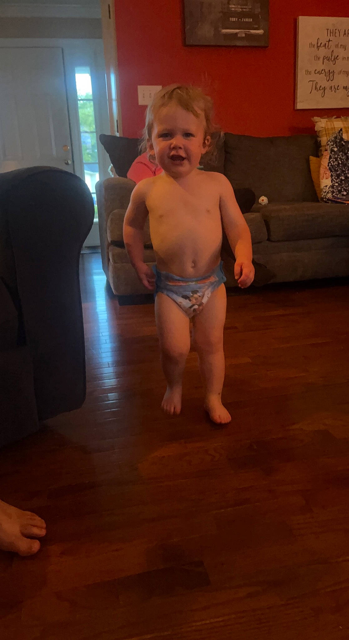 Toby is registered to the contest to win money with this photo: abdomen, baby, barechested, bathing, chest, couch, eye, floor, flooring, hardwood, human_leg, knee, navel, person, smile, stomach, thigh, thumb, toddler, trunk