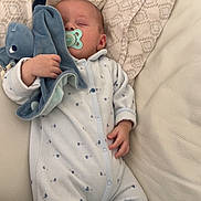 Eden participe au concours pour gagner de l'argent avec cette photo : baby, sleeping, pacifier, plush_toy, onesie, couch, pillow, blanket, infant, child, resting, comfort, soft_toy, indoor, peaceful, cozy, clothing, hand, face, relaxation