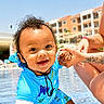 toddler, child, smiling, swimsuit, blue, pool, water, tattoo, adult, holding_hands, outdoor, sunny, resort, building, vacation, happy, curly_hair, person, summer, playful