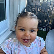Mina participe au concours pour gagner de l'argent avec cette photo : toddler, child, smile, happy, face, hair, shirt, patterned_clothing, outdoor, chair, table, fence, balcony, daylight, person, cute, baby, skin, expression, sitting