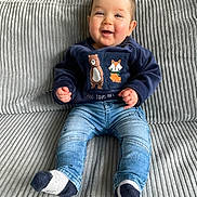Timeo a rejoint le concours — aidez-le/la à gagner de superbes lots ! baby, child, smiling, sitting, couch, clothing, socks, denim, sweatshirt, indoor, happy, face, person, cute, infant, furniture, casual, cozy, portrait, home