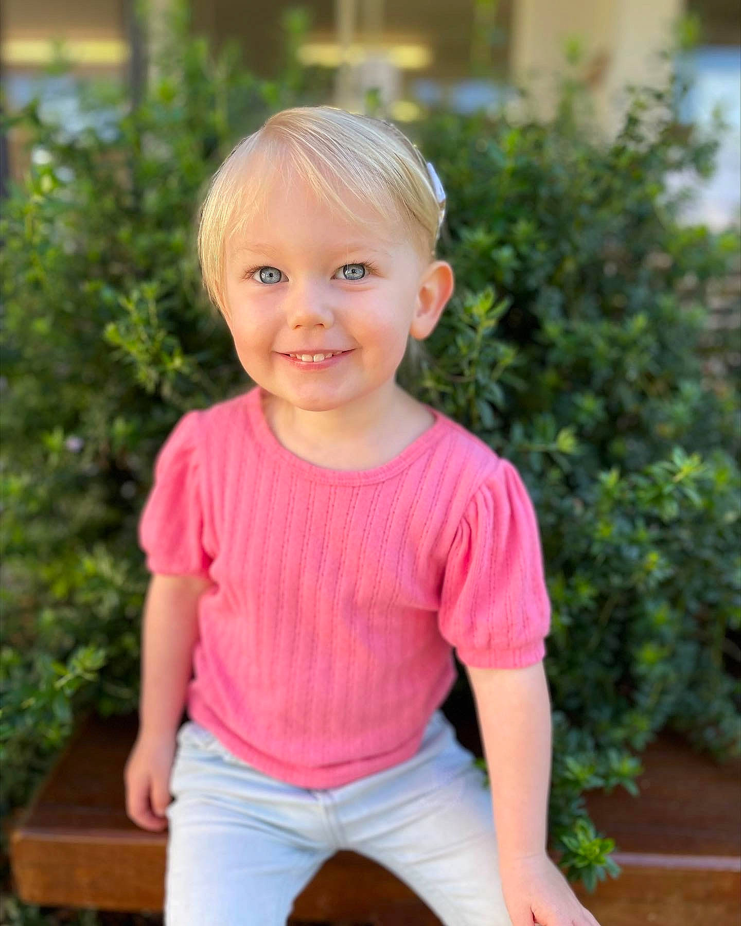 Aloy is registered to the contest to win money with this photo: arm, baby_toddler_clothing, chin, facial_expression, grass, hairstyle, happy, head, joy, mammal, neck, person, pink, plant, shoulder, sleeve, smile, standing, t_shirt, thigh