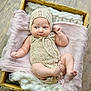 baby, infant, knitted_clothing, bonnet, wooden_box, wool, pink_cloth, soft_texture, newborn, cute, portrait, indoor, person, skin, small_feet, hands, lying_down, cozy, comfortable, child