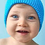baby, child, blue_eyes, smile, hat, knit_hat, portrait, close_up, happy, cute, infant, skin, face, blue_background, headwear, young_child, expression, teeth, cheeks, indoors