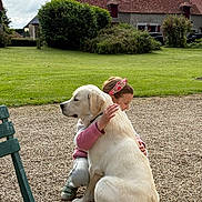 Aston participe au concours pour gagner de l'argent avec cette photo : child, girl, dog, labrador, yellow_labrador, hugging, affection, outdoor, garden, courtyard, grass, lawn, gravel, bench, rural, building, old_house, tile_roof, portrait, summer