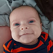 Sylas is registered to the contest to win money with this photo: baby, infant, face, blue_eyes, smile, striped_clothing, navy, orange, blanket, close_up, cute, child, portrait, soft, lying_down, young, expression, skin, head, person