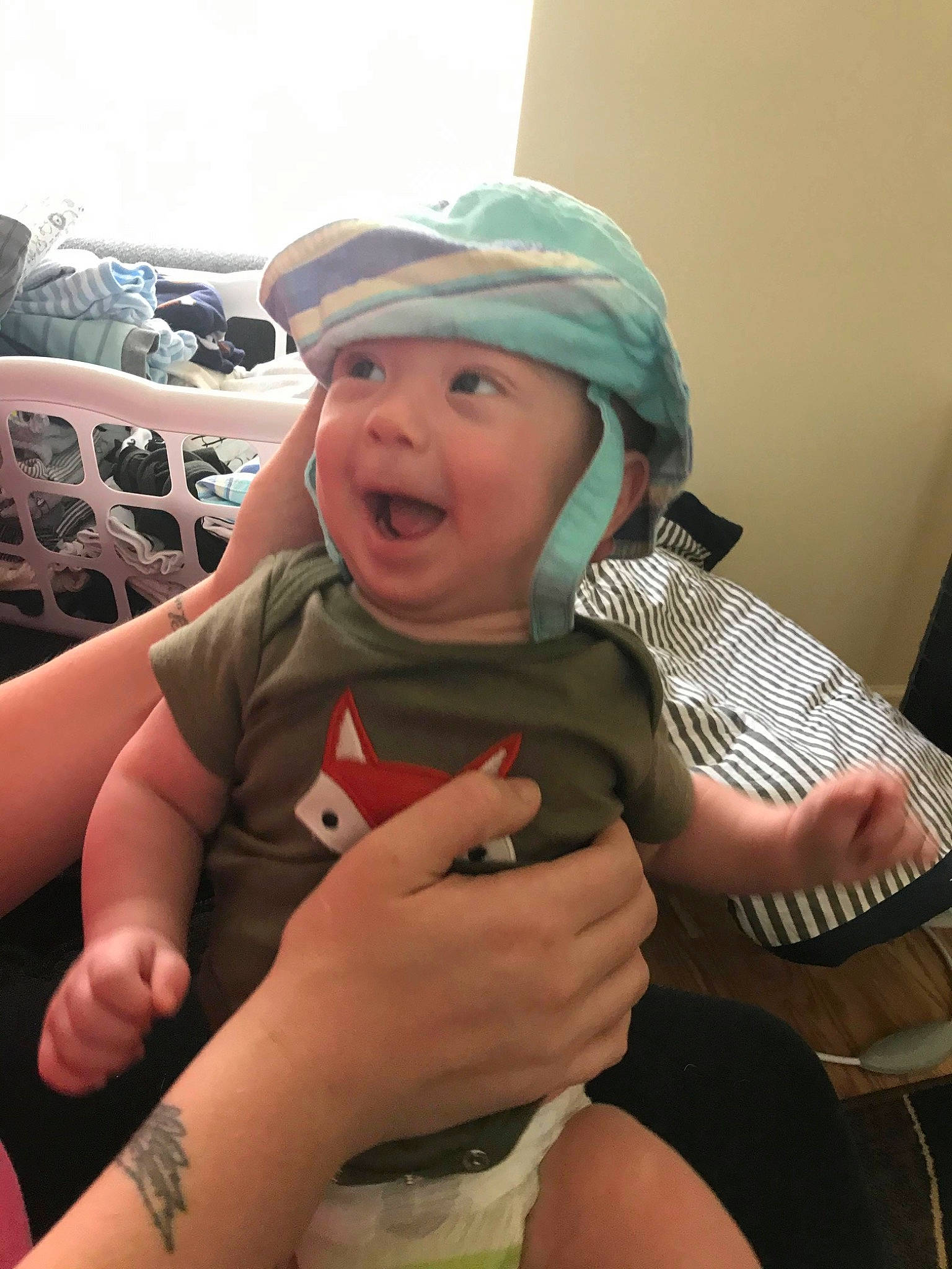 Neyland is registered to the contest to win money with this photo: arm, baby, child, finger, hand, hat, headgear, headwear, leg, person, smile, thumb, toddler, vacation