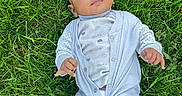 Ali Xavian is registered to the contest to win money with this photo: baby, barefoot, blue, child, clothing, cute, face, grass, greenery, head, infant, lying_down, nature, outdoor, pajamas, person, skin, small_hands, summer, white