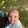 baby, child, infant, smiling, face, blue_eyes, outdoor, grass, nature, portrait, close_up, cuddling, parent, adult, arms, gray_clothing, long_sleeves, sunlight, happy, family
