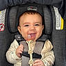 baby, child, infant, smiling, happy, car_seat, safety_harness, pacifier, toy, sitting, portrait, face, eyes, hands, clothing, long_sleeves, vehicle_interior, padded_seat, closeup, photograph