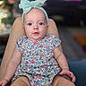 Stormi joined the competition — help win amazing prizes! baby, child, headband, bow, floral_clothing, onesie, legs, person, indoor, living_room, television, blurred_background, skin, cute, infant, portrait, sitting, hand, face, expression