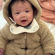 Ellie joined the competition — help win amazing prizes! baby, child, cute, fuzzy_clothing, hood, smiling, face, infant, one_piece_outfit, toddler, warm_clothing, indoors, soft_texture, hands, portrait, happy, cozy, cute_expression, light_skin, sitting