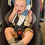 baby, infant, car_seat, smiling, happy, seatbelt, buckle, socks, legs, chubby_cheeks, hand, headrest, safety_tags, clothing, portrait, closeup, indoor, candid, toy, high_angle