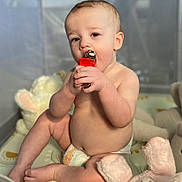 Matt is registered to the contest to win money with this photo: baby, bare_chest, bell, chewing, child, closeup, curious, cute, diaper, face, hand, indoor, infant, play_mat, plush_toy, sitting, skin, soft_toy, toy, young_child