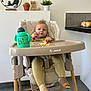 Timéo participe au concours pour gagner de l'argent avec cette photo : baby, high_chair, food, sippy_cup, kitchen, floor, socks, baby_clothing, face, person, furniture, plant, cactus, wooden_decor, cat_decor, countertop, onions, indoor, expression, mischievous