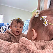 Isabella joined the competition — help win amazing prizes! baby, child, mirror, reflection, flower_crown, daisy, fuzzy_clothing, brown, indoor, room, laundry, window, curtain, happy, smiling, face, head, person, cozy, cute