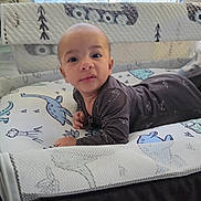 Ezekiel joined the competition — help win amazing prizes! baby, infant, child, crib, nursery, mattress, blanket, dinosaur, pajamas, portrait, face, smiling, lying_down, indoors, home, furniture, window, curious, soft_lighting, photography
