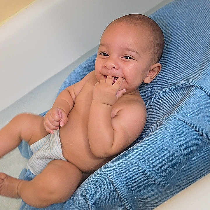 Ezekiel joined the competition — help win amazing prizes! baby, infant, child, smiling, happy, portrait, sitting, blue_seat, diaper, barefoot, hand, fingers, indoor, home, close_up, relaxed, playful, facial_expression, baby_chair, photography