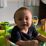 Jay is registered to the contest to win money with this photo: baby, child, indoor, activity_center, toys, smiling, face, curtains, window, cross, fan, furniture, person, colorful, seat, play, happy, young_child, infant, home