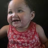 toddler, child, smiling, happy, face, portrait, red_dress, floral_pattern, baby, cute, innocence, dark_background, closeup, skin, hair, earrings, expression, person, young_child, cheerful