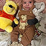 baby, child, plush_toy, winnie_the_pooh, overalls, mittens, baby_booties, blanket, soft_texture, smile, face, indoor, cute, lying_down, cozy, toy, childrens_clothing, person, infant, comfort